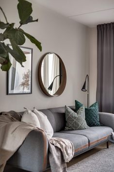 a living room filled with furniture and a round mirror on the wall next to a window