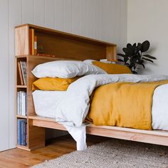 a bed with yellow and white pillows on top of it next to a book shelf