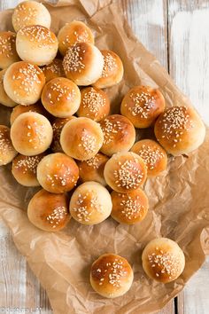 small buns with sesame seeds are on a piece of wax paper