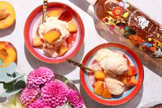 two bowls filled with ice cream and peaches on top of a table next to flowers