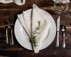 a white plate topped with two napkins next to silverware and a glass filled with water