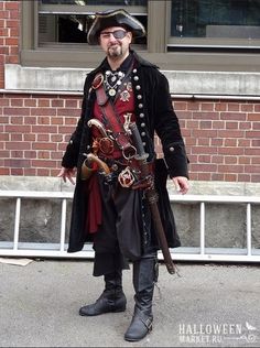 a man dressed in pirate costume standing next to a brick building with his hands on his hips