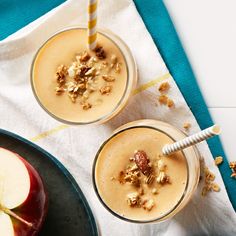 two glasses filled with apples and granola on top of a blue towel next to an apple