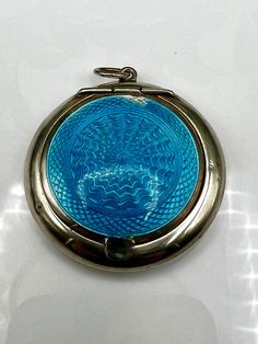 a blue glass pocket watch sitting on top of a white table next to a clock