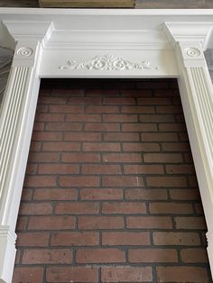 a white fireplace with red bricks and a clock on top