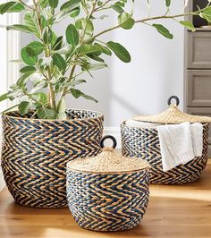 three woven baskets with handles are sitting on the floor next to a potted plant