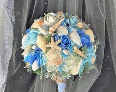 a bridal bouquet with seashells and blue flowers on the bride's veil