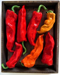 four red and yellow peppers in a wooden box