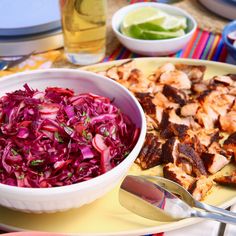 a bowl of red cabbage next to a plate of grilled chicken and coleslaw