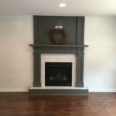 an empty living room with a fireplace and wreath on the mantle