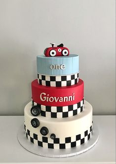 a three tiered cake decorated with cars and checkered paper on the bottom layer