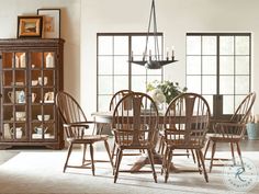 a dining room table with six chairs and a china cabinet in the backround