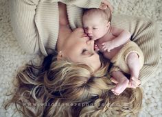 a woman laying on top of a bed holding a baby