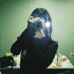 a woman taking a selfie in front of a mirror while holding a camera up to her face