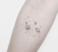 an arm tattoo with planets and stars on the left side of it, in black ink