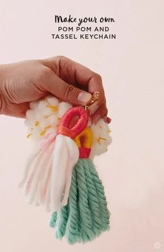 a hand holding a keychain that has been made with yarn and pom - pom