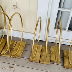 three gold metal racks sitting on top of a wooden floor next to a white door