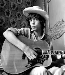 a man with a cowboy hat playing an acoustic guitar