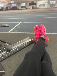 a person's feet resting on a metal bar in an empty parking garage area