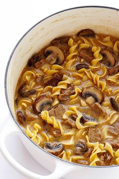 a pot filled with pasta and mushrooms on top of a stove