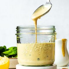 a spoon is pouring dressing into a jar