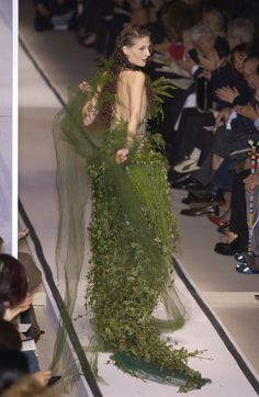 a model walks down the runway in a green dress with leaves and vines on it