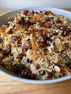 a white bowl filled with lots of food on top of a wooden table