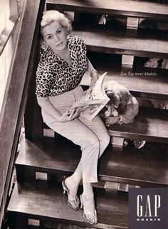 a woman is sitting on the stairs reading a book and holding a stuffed animal in her hand