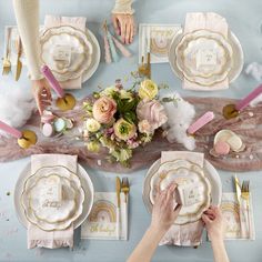 the table is set with pink and gold plates, napkins, and place settings