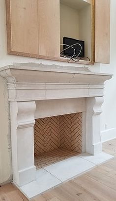 an unfinished fireplace in the corner of a room with wood flooring and white walls