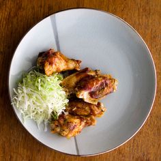 a white plate topped with meat and veggies on top of a wooden table