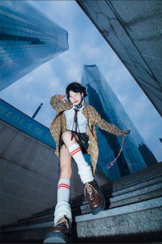 a woman is posing on the steps in front of tall buildings