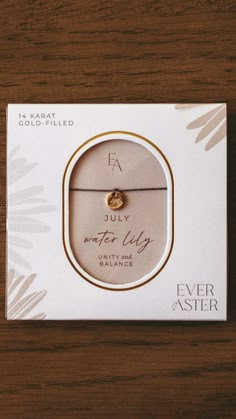 an unopened bracelet with a gold charm on it sitting in front of a box