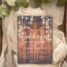 a rustic wooden wedding card with string lights and a deer antler on the front