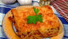 a piece of lasagna on a plate with garlic and parsley next to it