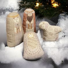 three stuffed animals sitting in the snow next to a christmas tree