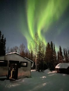 the aurora bore is seen in the sky above a cabin