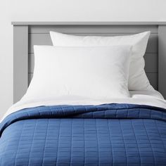 a bed with white pillows and blue sheets