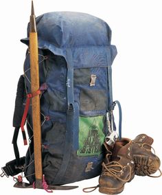 a back pack with hiking gear, boots and a stick sticking out of it's pocket