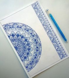 a blue and white drawing on paper next to a marker with a pen in it