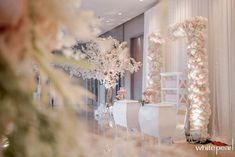 a room decorated with white flowers and pink decorations for a wedding or special event in the evening