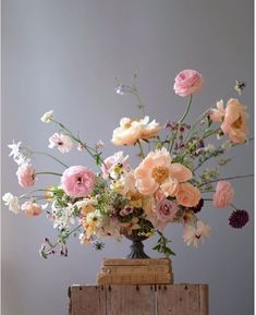 a vase filled with lots of flowers sitting on top of a wooden crate