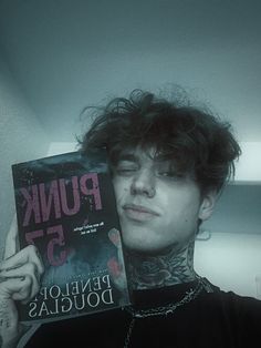 a man holding up a book in front of his face with punk 55 written on it