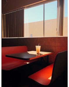 a table with a drink sitting on top of it next to two chairs and a window