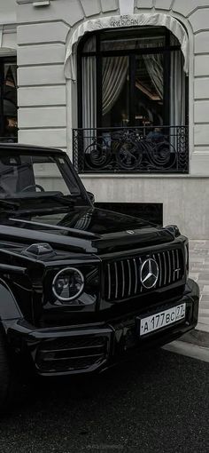 a black car parked in front of a white building with a bicycle rack on it