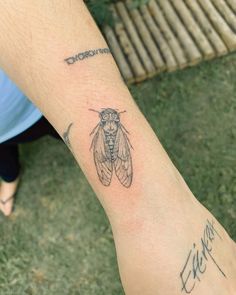 a person with a tattoo on their arm that has a small insect on it's wrist