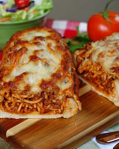 two slices of pizza sitting on top of a wooden cutting board next to a salad