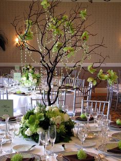 the table is set with white and green flowers, silverware, and place settings