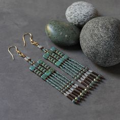 two pairs of earrings sitting next to some rocks