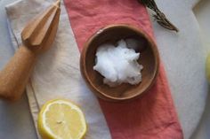 a wooden bowl filled with cotton next to lemons and an orange slice on top of a towel